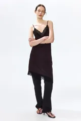 Vestido midi de punto interlock con ribete de encaje negro en el escote y bajo asimétrico. Tiene breteles spaghetti y escote en V.