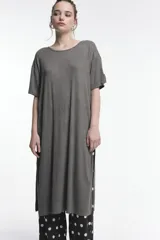 Vestido rib color gris, de corte oversized y largo por debajo de la rodilla. Presenta cuello a la base, manga corta, tajos laterales y un parche decorativo en la manga.
