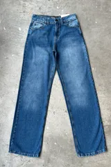 Jean de mezclilla azul de corte recto y tiro medio, con un gran parche negro en forma de estrella en el bolsillo trasero.