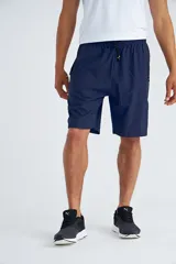 Short deportivo azul marino con cintura elástica ajustable con cordón, bolsillos laterales con cierre y logo estampado en la pierna izquierda.