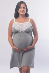 Camisón maternal de modal gris con detalle de puntilla blanca en el escote. Presenta breteles regulables con clip para lactancia y un diseño holgado pensado para la etapa de gestación.