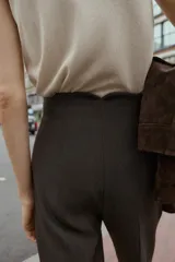 Pantalón de tiro alto color beige, con detalle de costuras marcadas en el delantero y la espalda. Incluye bolsillos delanteros de vivo y cierre frontal con cremallera, botón interior y gancho metálico.