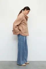 Tapado corto color beige de tejido grueso con cuello alto, cierre frontal con botones grandes veteados y bolsillos delanteros.