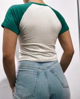 Remera corta blanca con mangas raglán de diferentes colores y estampado frontal con la leyenda "Malibu California A Beautiful Place".