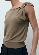 Jersey de punto fino color verde militar, sin mangas, con cuello asimétrico y detalle de joya decorativa en el hombro.
