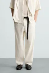 Pantalón de calce relajado confeccionado en tejido de viscosa y yute color tostado. Presenta cintura elástica ajustable con cordón, bolsillos laterales, bolsillos traseros de vivo y cierre frontal con cremallera y botón.