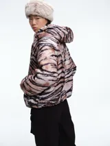 Campera acolchada con estampado animal print tipo tigre en tonos marrones y negros. Presenta cierre frontal, cuello alto, capucha y bolsillos delanteros con solapa.