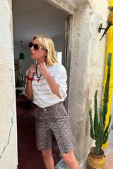 Blusa negra de manga 3/4 con cuello alto, confeccionada en algodón con paneles horizontales de encaje negro en el torso. Presenta un fajín integrado que se anuda a la cintura y puños con volado de encaje.