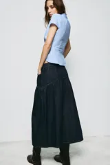 Falda midi de denim azul oscuro con tiro medio, bolsillos delanteros y costuras a contraste. Presenta un diseño con canesú estructurado y falda con frunces, cierre frontal con cremallera y botón metálico.