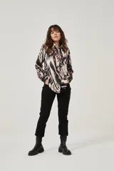 Camisa de manga larga con estampado abstracto en tonos marrones y blancos, cuello camisero y cierre frontal con botones. Puños con detalle de estampado animal print.