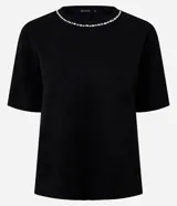Remera de corte regular confeccionada en gamuza sintética color negro, con mangas cortas y cuello redondo decorado con una aplicación de pedrería brillante.