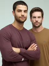 Remera de manga larga con cuello redondo, confeccionada en tejido de algodón con textura jaspeada. Presenta un pequeño logo bordado en el pecho y una etiqueta decorativa en el puño.