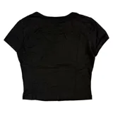 Remera tipo baby tee de corte ajustado, color negro, con estampado frontal en blanco de un corazón con alas y elementos urbanos.