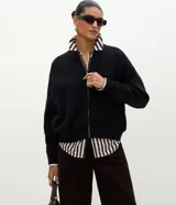 Campera de punto de corte regular y estilo oversized, confeccionada en una mezcla de viscosa, poliéster y poliamida. Presenta cierre frontal completo, mangas largas con puños acanalados y acabado acanalado en el ruedo.