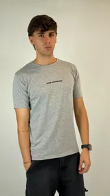 Remera gris melange de corte clásico, con cuello redondo y mangas cortas. Presenta un estampado pequeño y minimalista en el pecho con el logo de la marca.