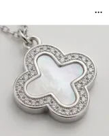 Collar de acero con dije en forma de flor de cuatro pétalos, con centro de nácar y borde pavé de circonias.