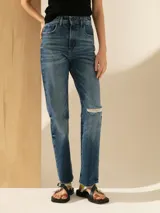 Pantalón de jean de tiro alto, corte recto, color azul medio con lavado parejo y un corte en la rodilla.