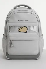Mochila de diseño funcional en color beige, con compartimento principal amplio, bolsillo frontal con ventana transparente y parche decorativo de capibara. Incluye múltiples bolsillos organizadores, correas ajustables y base reforzada en color marrón.