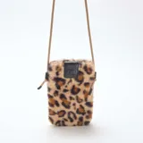 Bolso bandolera para teléfono de textura peluda con estampado animal print de leopardo. Cuenta con una solapa superior de cuero sintético negro y correa de cordón ajustable en color beige.
