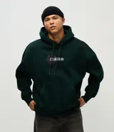Buzo con capucha de color verde oscuro, confeccionado en tejido con felpa. Presenta un diseño estampado en la espalda con motivos de dragón y flores en color fucsia.