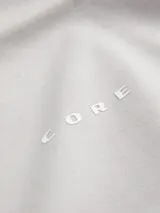 Remera de manga corta y cuello redondo con calce relajado. Presenta un diseño minimalista con la palabra 'CORE' estampada en el centro del pecho. Confeccionada en tejido interlock de tacto suave.