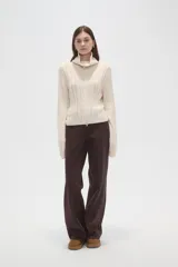 Saco de punto de algodón con diseño de trenzas, cuello alto y cierre frontal completo. Presenta un corte al cuerpo y mangas largas.