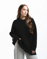Sweater negro de punto con cuello redondo y corte holgado. Diseño con motivo de zurcido en la manga izquierda.