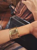 Brazalete rígido de bronce con acabado texturizado y diseño abierto ajustable.