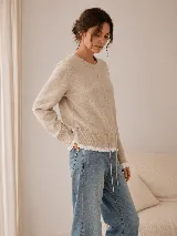 Cardigan de tejido de punto en color beige, con cuello redondo, cierre frontal de botones y mangas largas. Presenta detalles de puntilla en el ruedo y los puños, además de un lazo ajustable en la cintura.