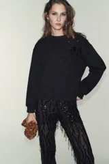 Sudadera de algodón con cuello redondo y manga larga, caracterizada por un detalle de flor con volumen confeccionada en organza sobre el hombro. Presenta terminaciones en rib en puños y ruedo.