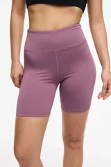 Short deportivo tipo biker de cintura alta, color violeta, con paneles laterales de microtul y bolsillos integrados.