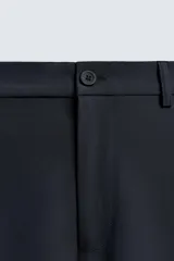 Pantalón regular fit color azul marino, confeccionado en tejido elástico. Cuenta con bolsillos frontales, bolsillos traseros de vivo con botón y cierre frontal con cremallera y botón.