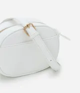 Cartera tipo camera bag pequeña, color marrón camel, de forma ovalada con superficie texturizada. Cuenta con correa ajustable larga, cierre principal con cremallera dorada y un pequeño bolsillo frontal con cremallera.