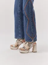 Sandalias de plataforma con taco cuadrado alto, confeccionadas en cuero metalizado color dorado. Presentan un diseño de tiras anchas cruzadas en el empeine y cierre con pulsera al tobillo.