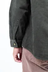 Camisa verde oliva de pana de algodón, corte recto, manga larga, cuello abotonado y bolsillo en el pecho.