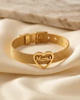 Pulsera de acero con baño de oro, compuesta por una malla metálica ajustable tipo cinturón y un dije central en forma de corazón con la palabra 'Mamá' calada en su interior.