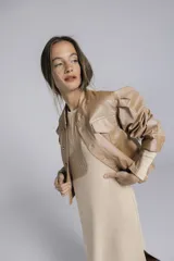 Campera color dorado metalizado, de corte clásico, con abotonadura frontal, bolsillos delanteros y mangas abullonadas.