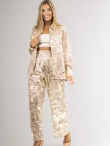 Conjunto de dos piezas compuesto por camisa de manga larga con cuello camisero y pantalón de corte recto y holgado. Ambas prendas presentan un acabado metalizado con efecto desgastado en tonos dorados.