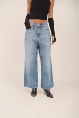 Jean de denim claro, tiro medio, con calce baggy y pierna ancha. Presenta costuras visibles.