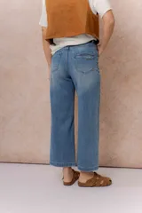 Pantalón de jean con corte wide crop y tiro alto. Presenta un lavado azul clásico con sutiles desgastes, pierna amplia con largo al tobillo, cierre frontal con botón y bolsillos funcionales.