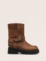 Bota de punta cuadrada realizada en cuero encerado color marrón, con hebillas en la caña, herrajes de níquel y fondo de suela negro.