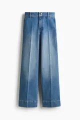 Jean de denim de algodón color azul con leve stretch, tiro alto, pierna amplia, bolsillos de parche traseros, pliegues delanteros y traseros, y doble botón en la cintura.
