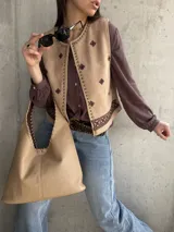 Chaleco de gamuza beige con bordados étnicos, detalles de tachas metálicas en los bordes y cierre abierto.