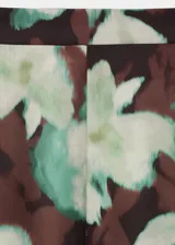 Pantalón largo estilo flare de tiro medio, con cintura elástica y forro interior, con estampado floral en tonos oscuros y verdosos.