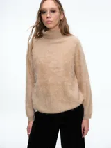 Sweater de cuello alto con textura peluda, confeccionado en tejido de punto suave y holgado, con mangas largas y puños ajustados.
