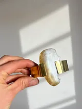 Brazalete rígido hecho a mano en bronce dorado con pieza irregular de nácar engarzada.