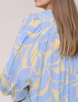 Blusa de gasa texturizada color celeste con estampado abstracto en tono amarillo, de silueta holgada y fluido diseño. Presenta escote en V con cuello a la base y abotonadura frontal con botones a tono. Cuenta con mangas largas abullonadas con puños elastizados.