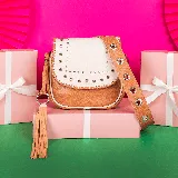 Bandolera de cuero vacuno color camel y blanco, con correa larga ajustable y removible con ojales metálicos. Tiene cierre superior y tapa con broche a presión. El interior está forrado y cuenta con un bolsillo con cierre y otro pequeño para el celular.
