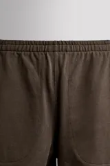 Short jogger marrón de corte relaxed fit, confeccionado en tejido compacto de algodón, con cintura elástica ajustable, bolsillos frontales en la cadera y bolsillo trasero de plastrón.
