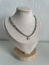 Collar de cristales facetados grises con pequeñas cuentas doradas y un dije central con piedra brillante y baño dorado.